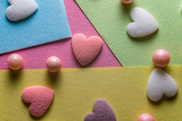 Tri-color sugar hearts on a pink background closeup.