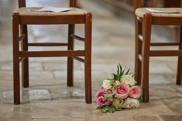 the bride’s bouquet lies on the floor near the wooden chairs