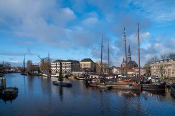 Fototapeta premium Museum harbor and Turfsingelgracht in Gouda with historic boats, De Roode Leeuw flour mill and the Gouwekerk.