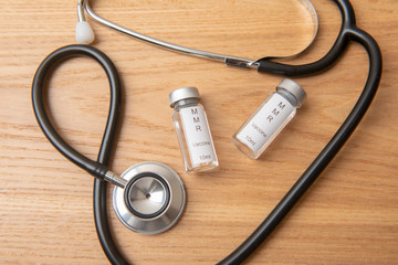 MMR vials with a stethoscope on a wooden background