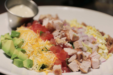American style Cobb salad with avocado, tomatoes, chicken breast, cheese, corn, and meat.