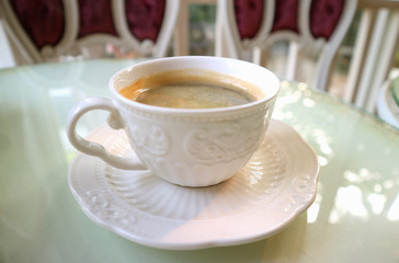 Cup of hot coffee served on white table	