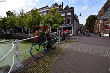 Delft, the netherlands, august 2019. The pretty and romantic canals. The aquatic plants create a green carpet, the bridges frame the flower boxes in warm and bright colors. Parked bikes.