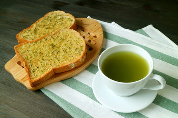 Closeup a Cup of Hot Green Tea with Garlic Butter Toasts on White and Green Napkin