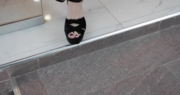 lady with black pedicure in fashionable high heeled shoes opens door and steps on tile stairs slow motion closeup