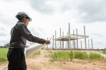 Asian manager of engineering architects in white helmet safety on construction site standing to...