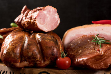 Composition of different smoked meat with spices and herbs on wooden background