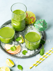 Green smoothie in glass with organic ingredients, vegetables on a light background with copy space. Selective focus. Food and drink, healthy dieting, nutrition, alkaline, vegan, vegetarian concept.