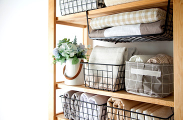Bed sheets, duvet covers and towels are folded vertically. Metal and fabric black baskets. The concept of housework and storage.