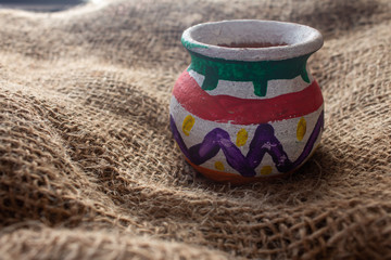 Handcrafted earthen pot over a sack bag. Clay vase made out of mud on cloth background.