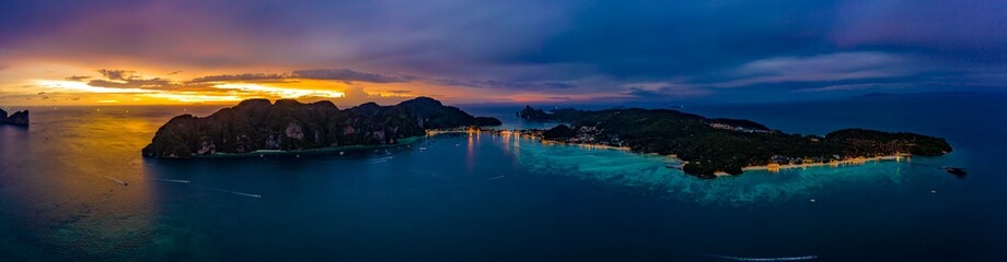 Aerial view of Phi Phi, Maya beach with blue turquoise seawater, mountain hills, and tropical green forest trees at sunset with Andaman sea  island in summer, Thailand in travel trip. Nature. Panorama