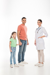Full length of pediatrician near father with daughter smiling at camera on white background