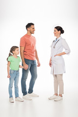 Obraz premium Full length of female pediatrician smiling at father with daughter on white background