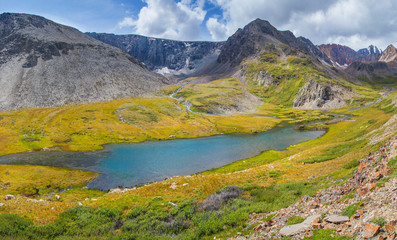 Fototapeta na wymiar Mountain valley, sunny summer day. The lake among the mountain tundra and green meadows. 