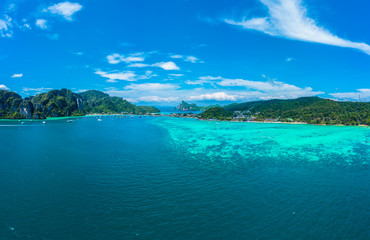 Naklejka na ściany i meble Top view of tropical island with limestone rocks and blue clear water. Aerial view of Tonsai bay with many boats and speedboats above coral reef. Phi-Phi Don Island, Thailand.