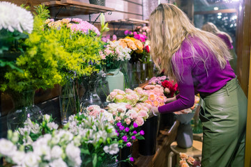 Female florist creating beautiful bouquet in flower shop, close up