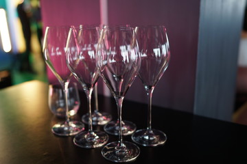 Set of empty wine glasses on a table with a red light in the background at a restaurant party.