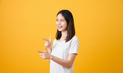 Smiling Asian woman stand and pointing finger on orange background.