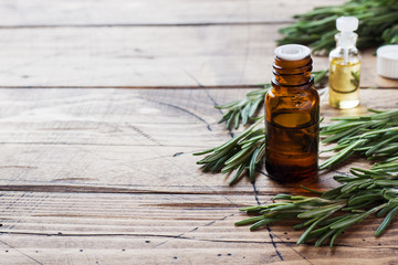 Rosemary essential oil in a glass bottle with fresh branch rosemary herb on wooden table for spa,aromatherapy and bodycare.Copy space.
