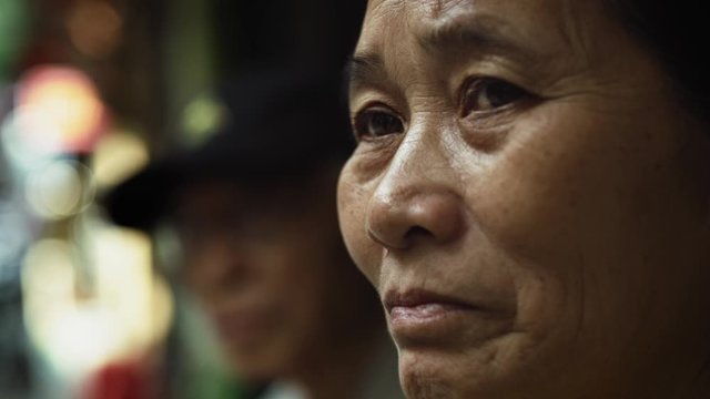 Handheld view of Vietnamese senior woman in the street. Shot with RED helium camera in 8K