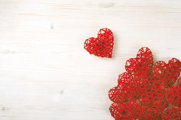 Beautiful red wicker hearts on the light wooden background. St Valentine's concept with copy space.