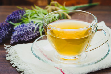 A cup of lavender tea with a bunch of lavender in the background