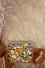 Beautifully decorated Easter treat in a wooden plate with a gift ribbon with palm branches on a background of mint craft paper with copy space.Concept of Easter gifts. palm Sunday. Food photo