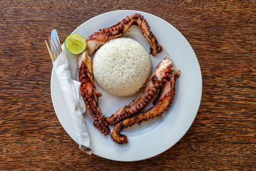 Fried octopus tentacles with white rice on a plate, close up