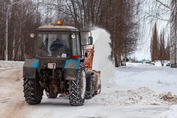 Snow cleaning tractor removing snow with front shovel on a city street after blizzard. Russia,...