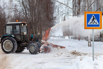 Snow cleaning tractor removing snow with front shovel on a city street after blizzard. Russia,...