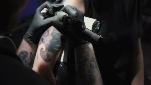 Footage of man doing tattoo of snake on woman in studio