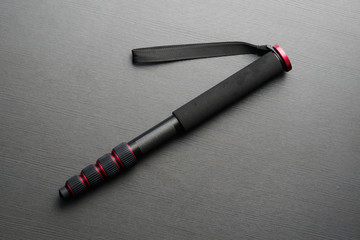 Black modern high-quality monopod on a dark table.