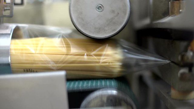 Close up of spaghetti packages running on an automated conveyor belt machinery in an Italian pasta factory.  Food.