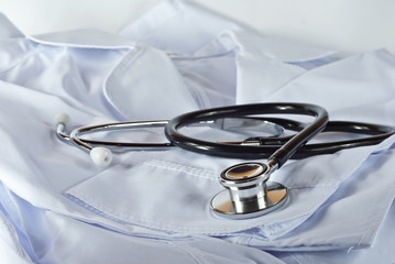 Black stethoscope on white medical gown. Medical equipment on a white background.