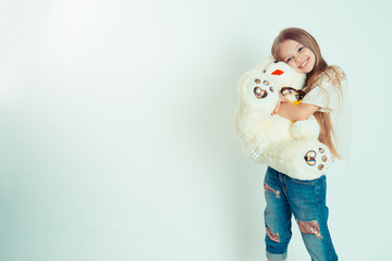 Little girl hugging teddy bear is looking at the camera.