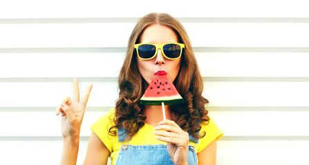 Portrait young woman eating ice cream shaped watermelon over white background