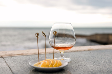 a glass of cognac or brandy, against the sea.