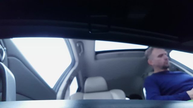 Caucasian man opens car glove box and pulls out documents, then takes them back. View from glove compartment