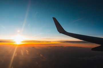 Airplane flying above the clouds at sunset.