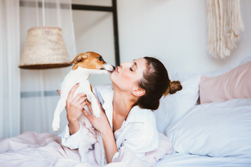 Woman and dog play on the bed.