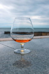 a glass of cognac or brandy, against the sea.