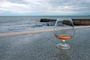 a glass of cognac or brandy, against the sea.