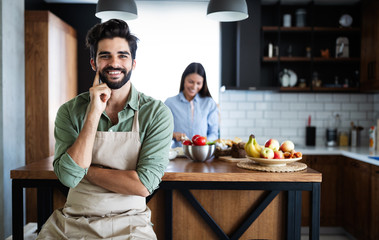 Portrait of happy young couple cooking together in the kitchen at home.