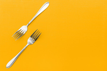 Stainless steel cutlery on a colored background. Two silver forks for food. Cooking utensils. Restaurant menu concept.