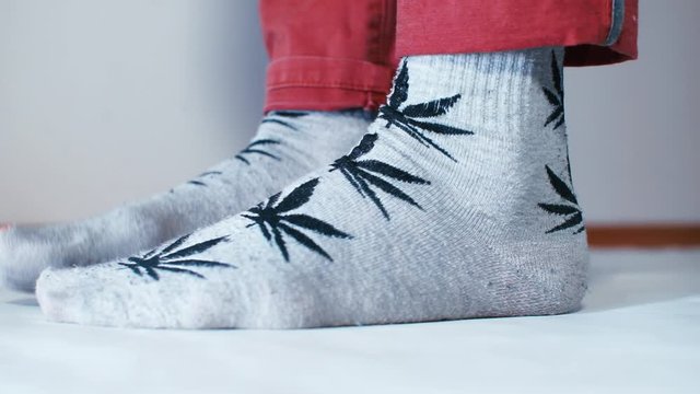 The legs of a man in socks full of holes step in place.