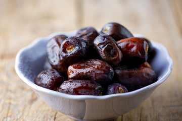 Beautiful juicy date with water drops. Fresh dates plucked from a tree in a plate. Dried dates on a wooden table, still life. Vegetarian food. Sweet snack. Large sweet dates close-up. Useful sweets fo