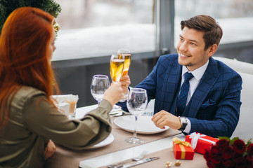 beautiful caucasian couple celebrating saint valentines day in restaurant, sit at table, enjoy having dinner together, man in tuxedo and woman in dress. celebration, relationship, love concept