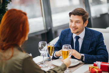 romantic pastime of young beautiful caucasian couple in restaurant. redhaired attractive lady and handsome bearded man in tuxedo on a date. tender relationship between two people in love