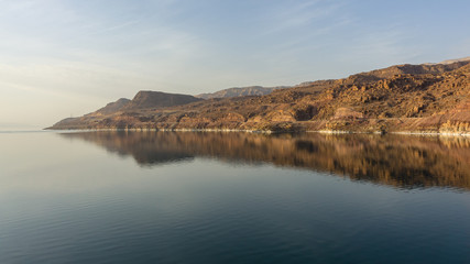 Magical sunset on Dead Sea in Jordan. Golden mountains are reflected in Dead Sea. Concept of pacification, tourism and ecology. There is place for your text