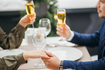 close-up of couple clinking glasses with champagne in rich representative restaurant. couple having dinner together, on a date